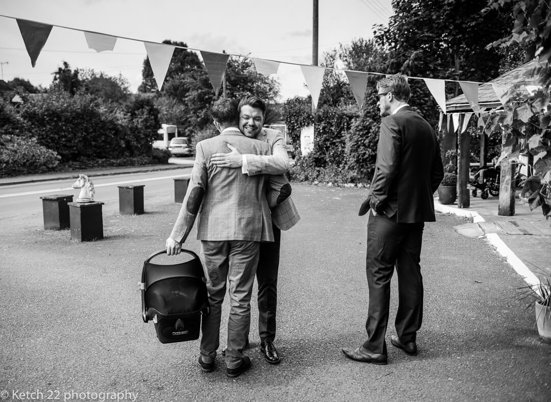 Groom greeting one of his ushers at documentary wedding