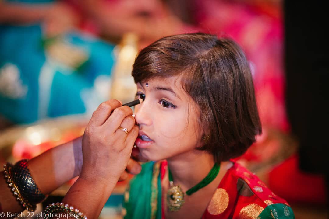 Little girl having make up applied at Indian wedding