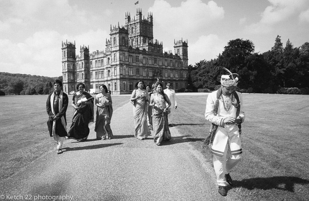 Groom walking in front of Highclere Castle at Hindu wedding