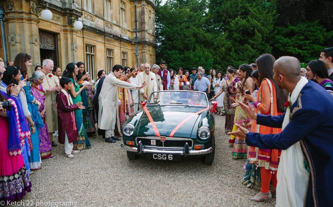 Bride and groom leaving wedding in green sports car 