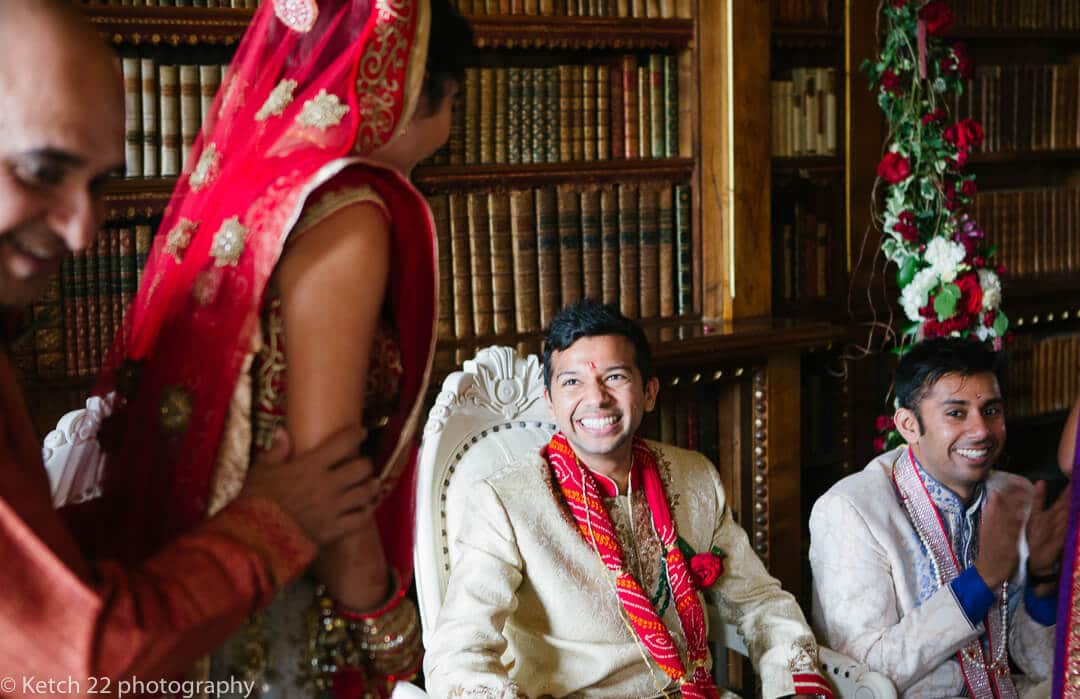 Groom wearing red flowers looking at bride 