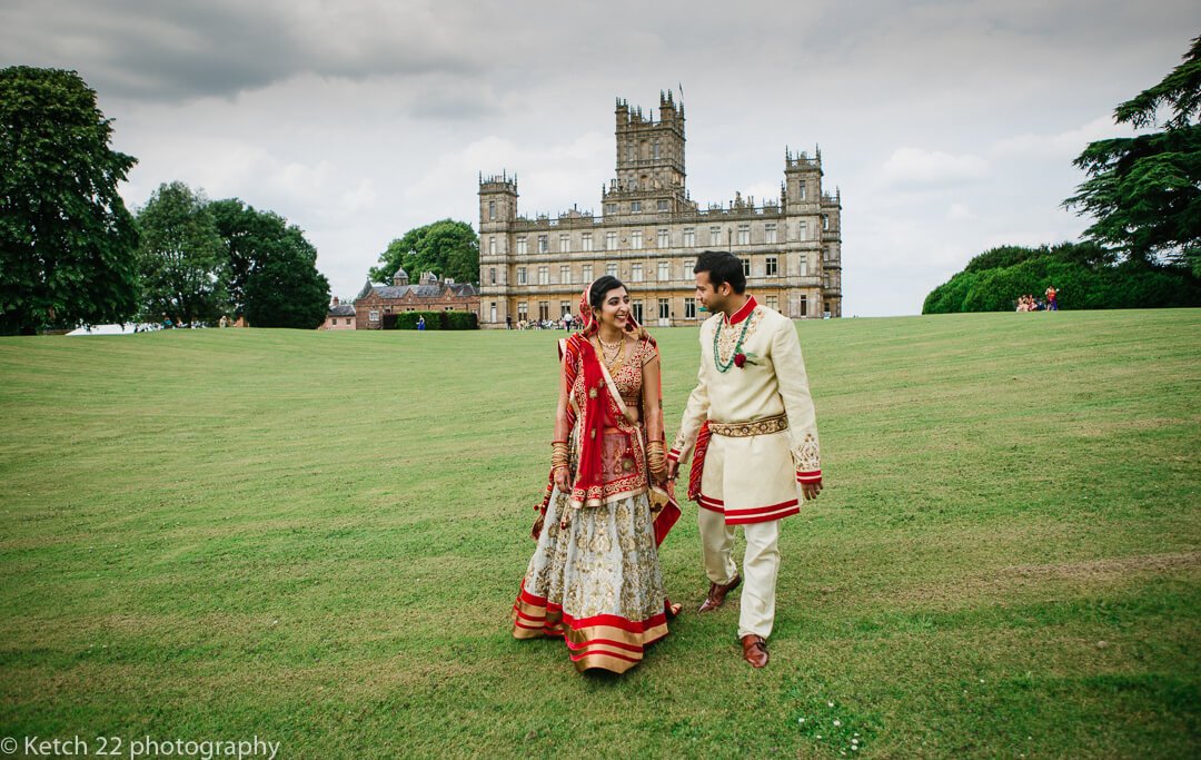 Bride and groom walking on lawn at Highclere Castle