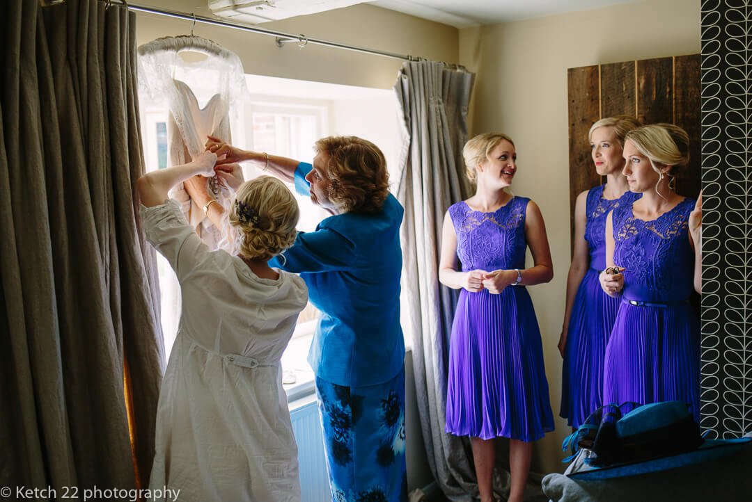 Story telling photo of bride and mother getting wedding dress ready