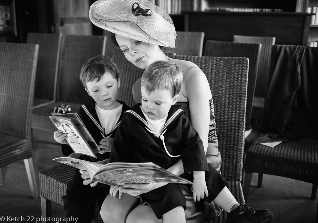 Mother with two small boys sat on her lap reading at Herefordshire wedding