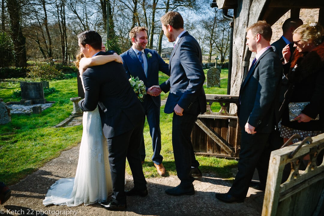 Bride and groom greet wedding guest outside church 