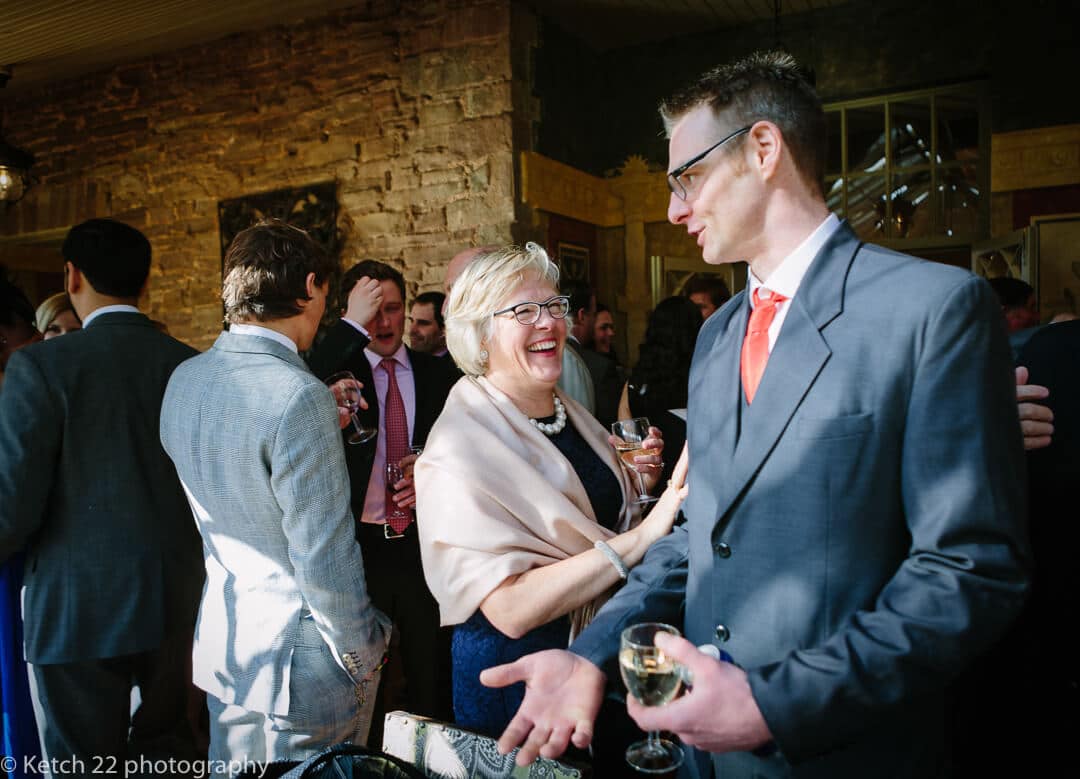 Wedding guests at reception drinking and laughing