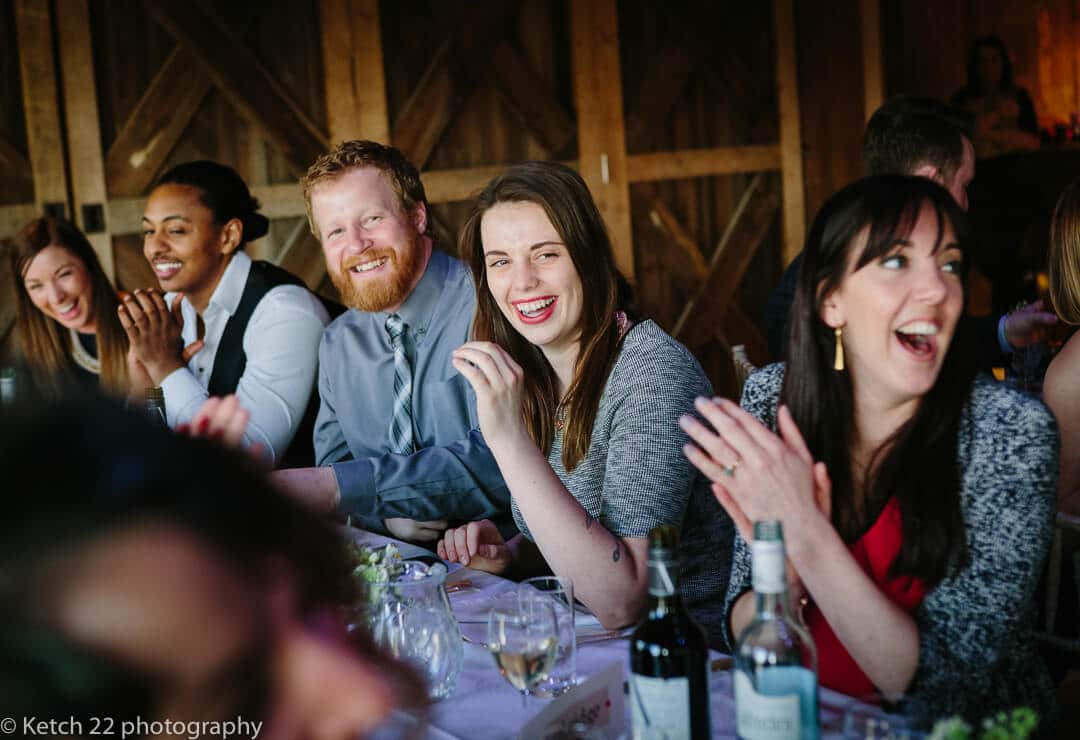 Wedding guests cheering at speeches at barn wedding