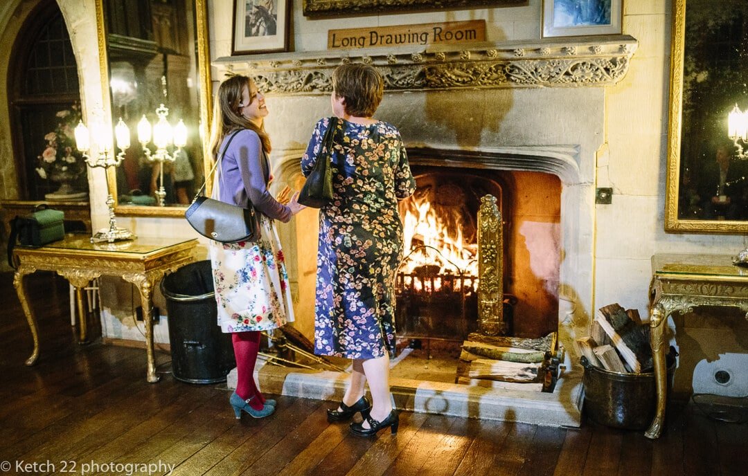 Guests warming themselves by warming fire at Winter wedding at Berkeley Castle
