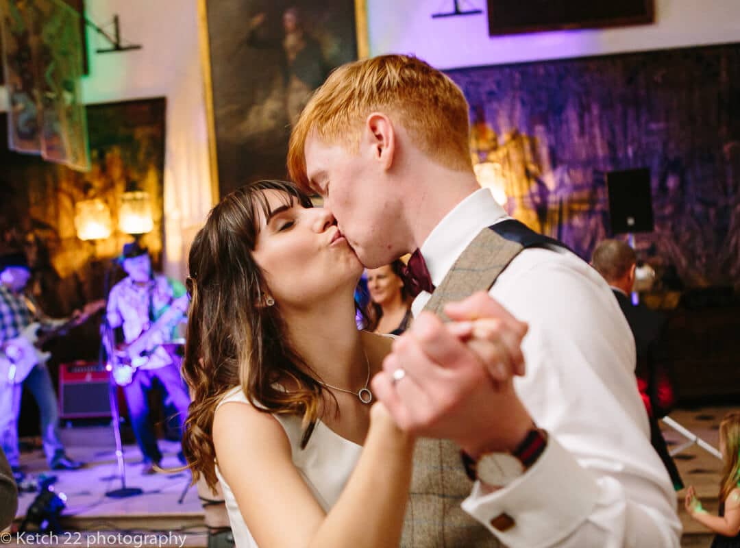 Candid photo of bride and groom kissing at wedding reception