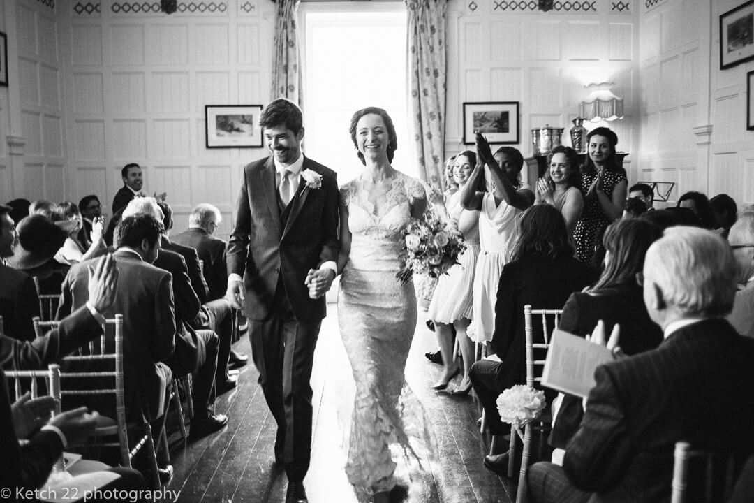 Happy bride and groom leaving wedding ceremony room at Homme House