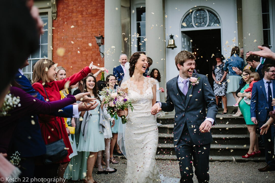 Colourful photo of bride and groom getting showered with confetti at recommended wedding venue Homme House