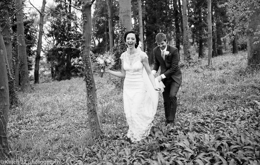 Groom carrying brides dress as she is laughing