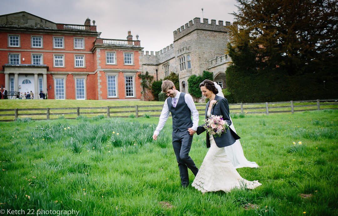 Bride and groom walking in front of recommended wedding venue, Homme House in Herefordshire