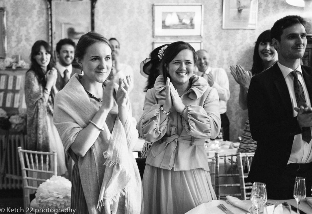 Smiling wedding guests clapping as bride and groom enter dinning room