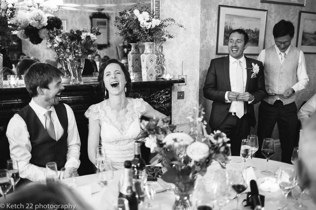 Expressive bride laughing out loud at wedding speeches