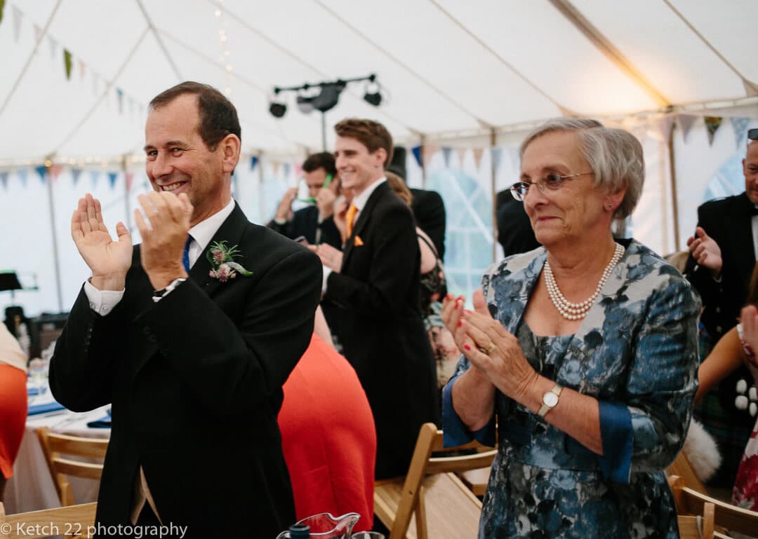 Wedding guests cheer bride and groom as they enter marquee