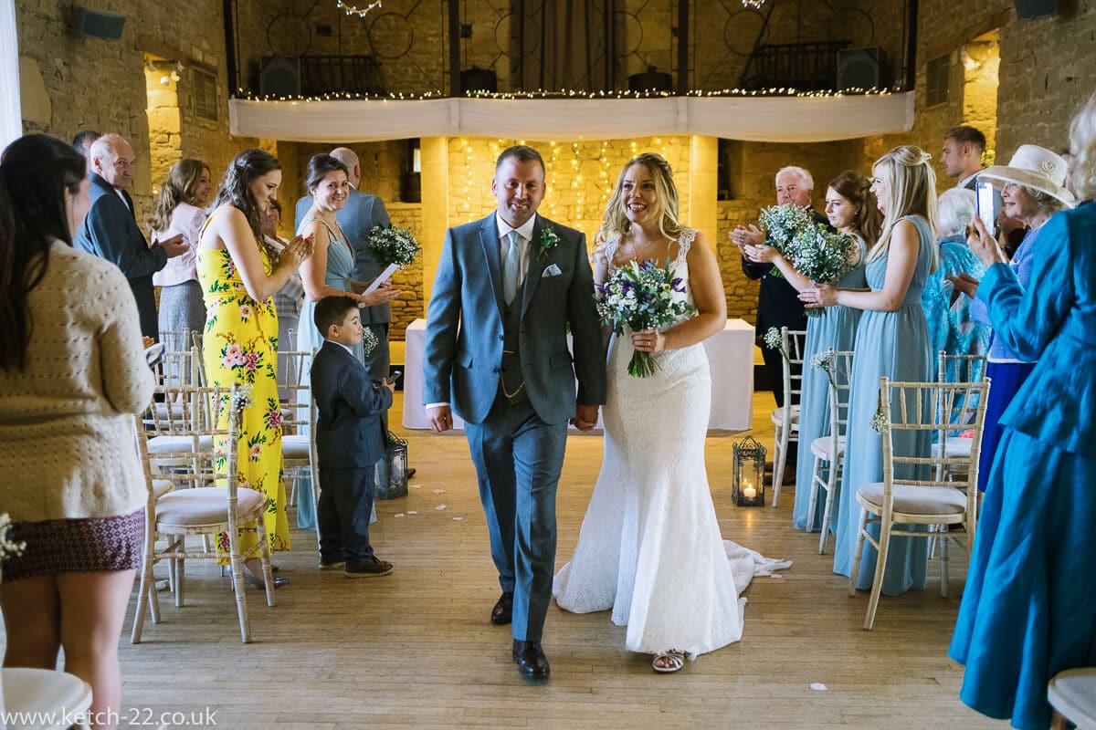 Bride and groom leaving ceremony at Wedding at The Great Tythe Barn