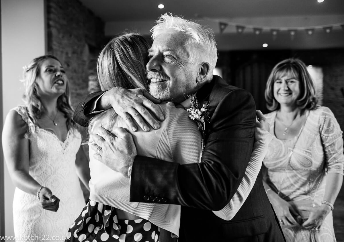 Wedding guest getting hug from father of bride