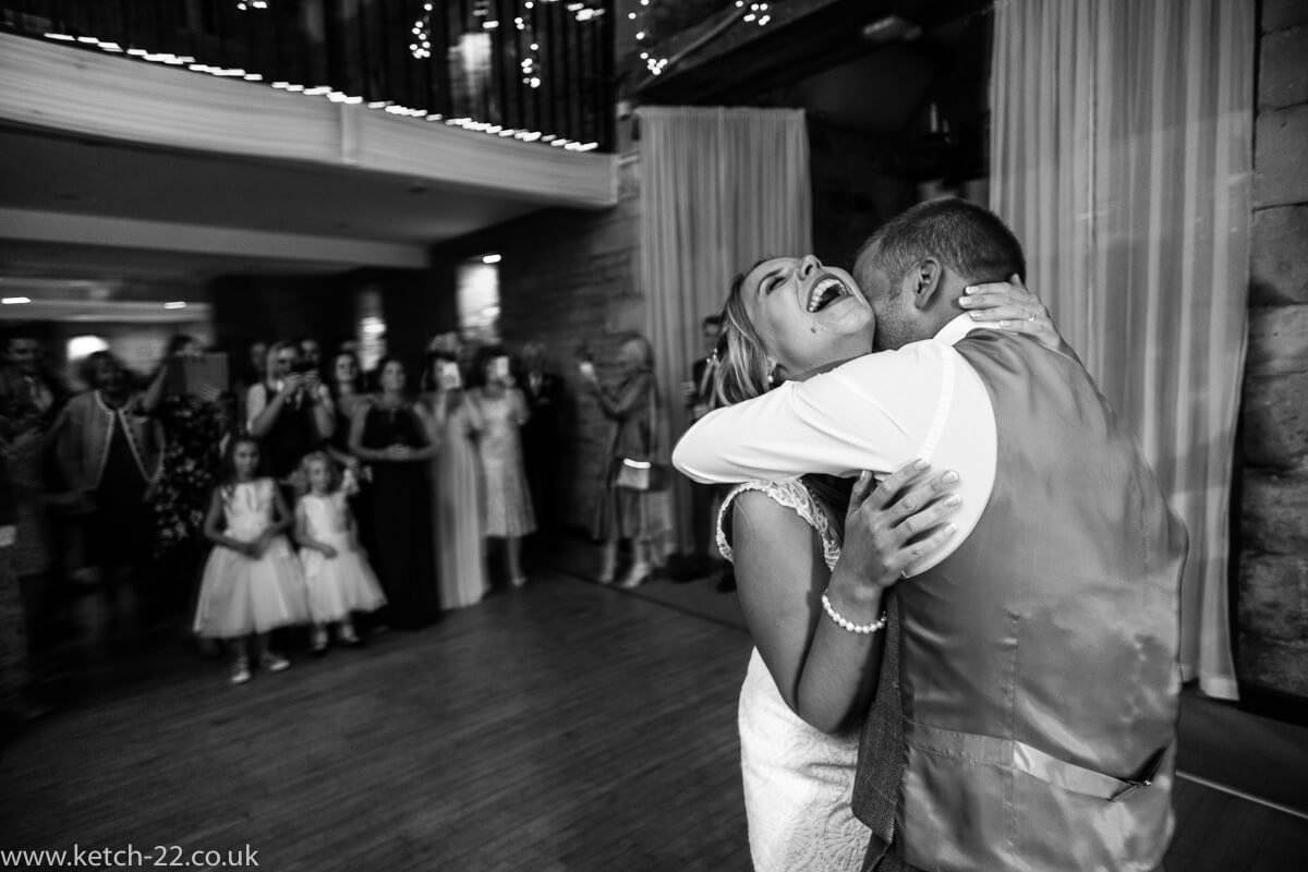 Laughing bride dancing with groom at the great Tythe Barn