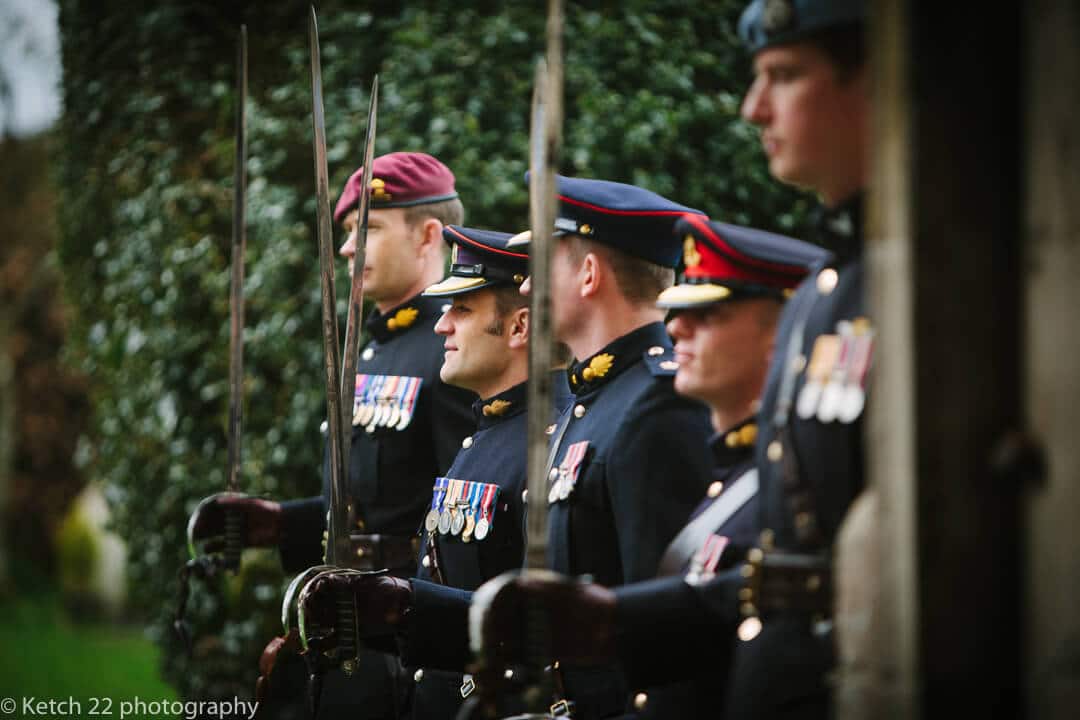 Groomsmen in army uniforms with swords at wedding