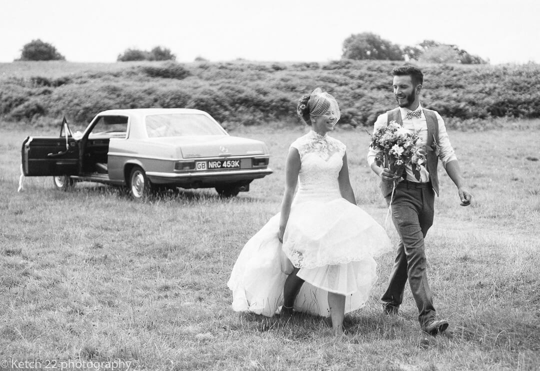 Bride and groom walk from wedding car at rural wedding in Herefordshire 
