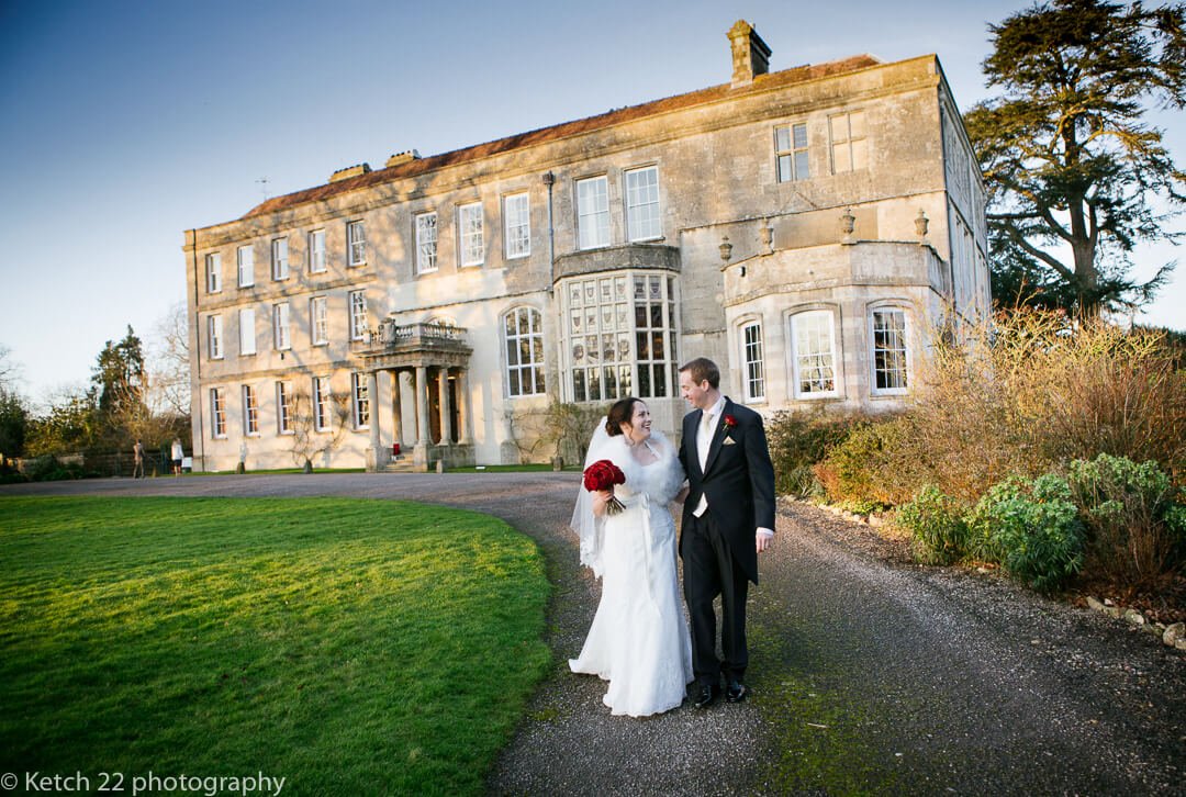 Bride and groom walking on path in front of Elmore Court wedding venue