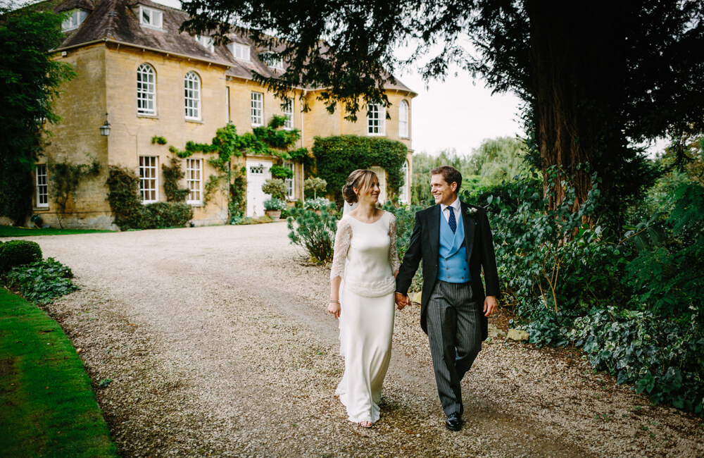 Bride and groom walking in front of Upper Court wedding venue Gloucestershire