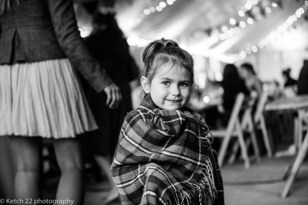 Cute little girl wrapped in blanket at summer wedding