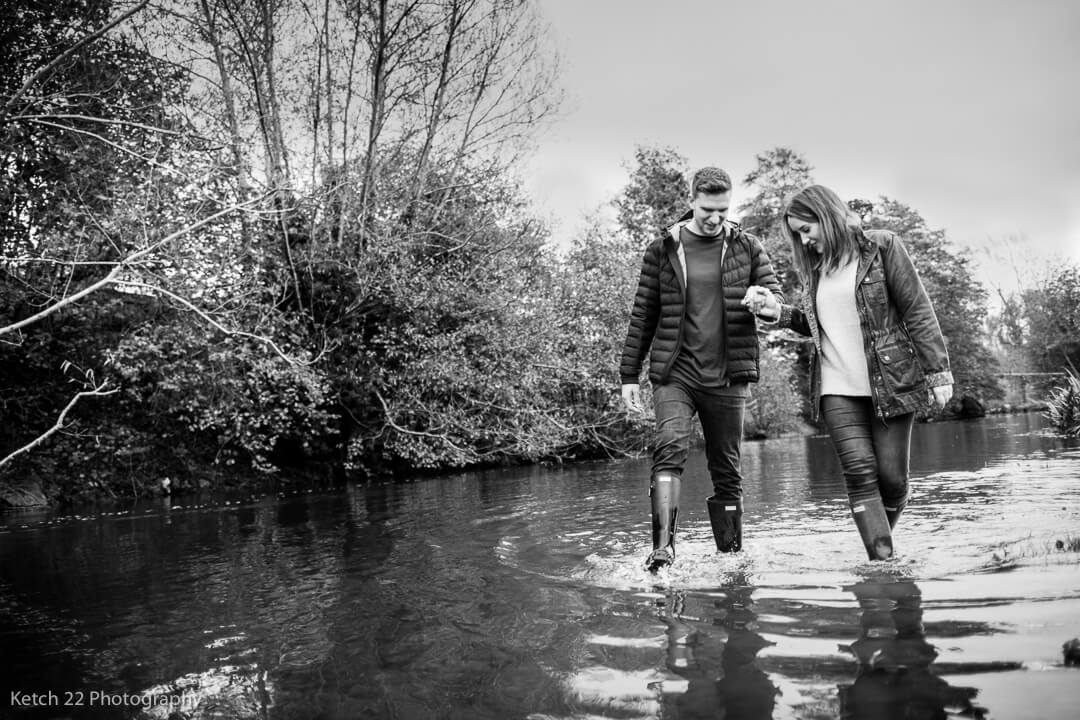 Engaged couple walking in river in Herefordshire