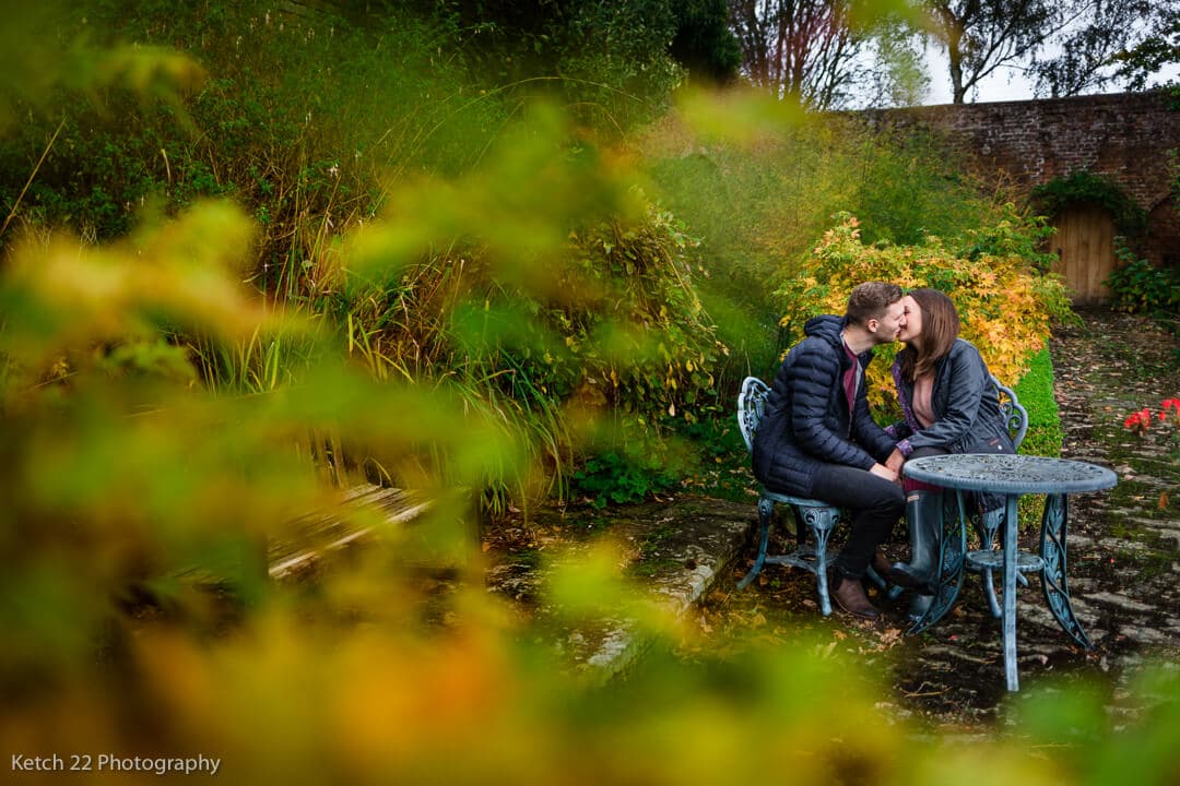 Engaged couple kissing in garden in the autumn