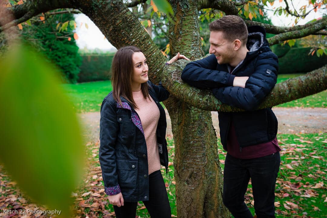 Young couple leaning on tree at rural engagement session Herefordshire