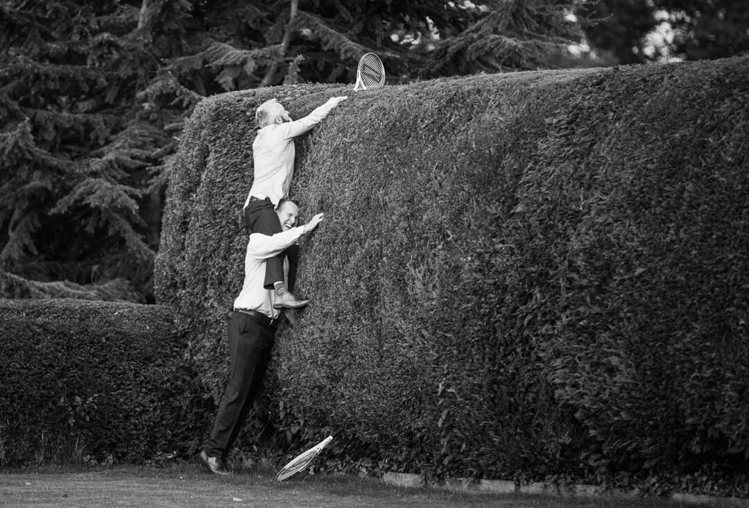 Wedding guests trying to retrieve tennis ball in bush at North Cadbury Court