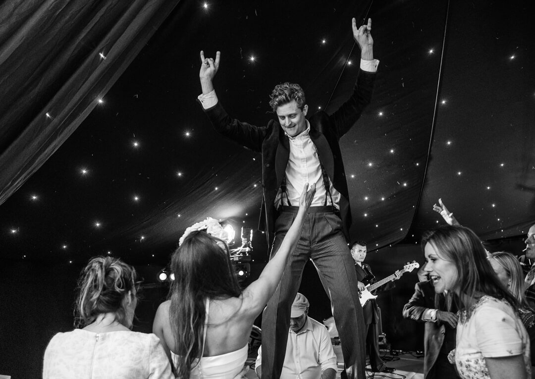 Groom standing on table dancing at wedding reception