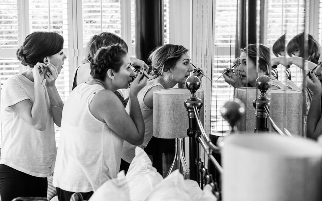 Bridesmaids putting make up on in mirror at Hilles House Wedding