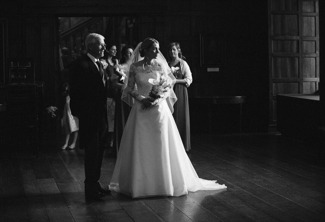 Moody black and white photo of bride waiting just before wedding ceremony