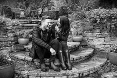 Engaged couple laughing on steps in garden