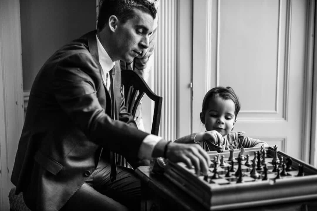 Reportage wedding photograph of child and father playing chess