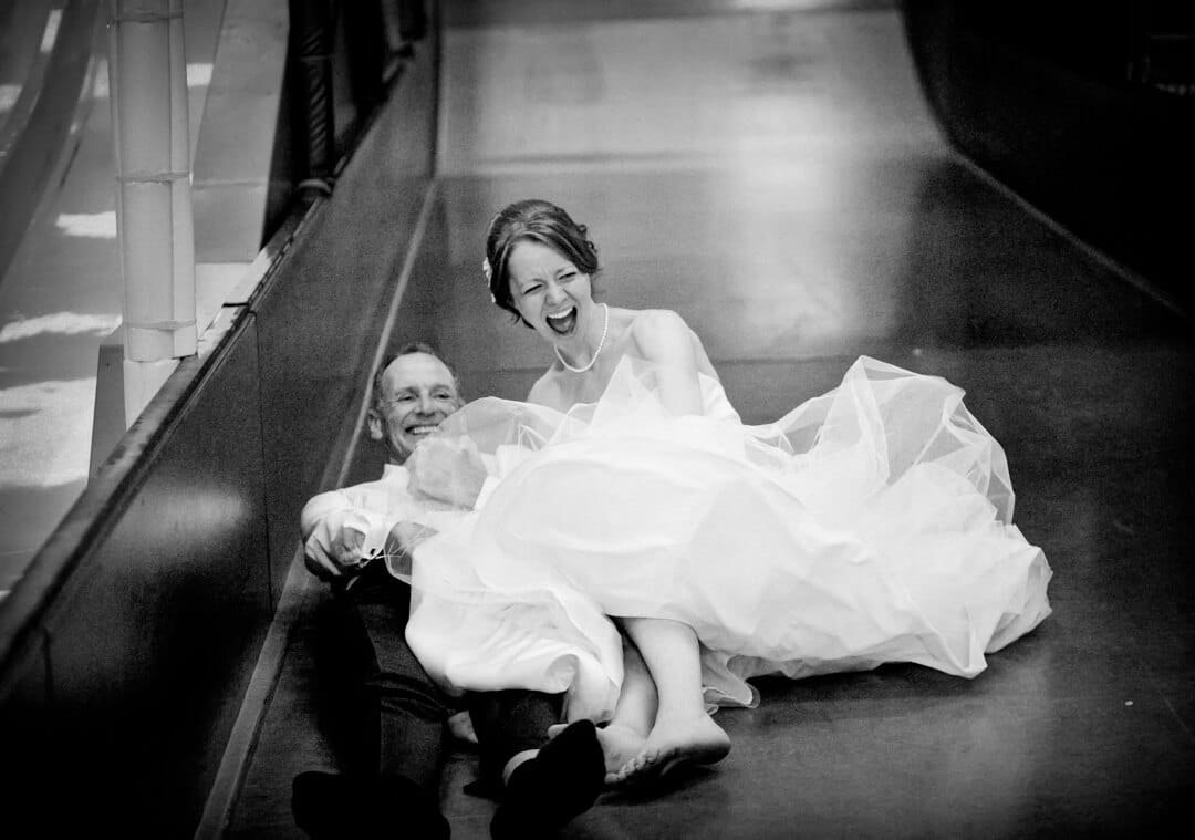 Bride and father coming down a big slide for documentary weddings