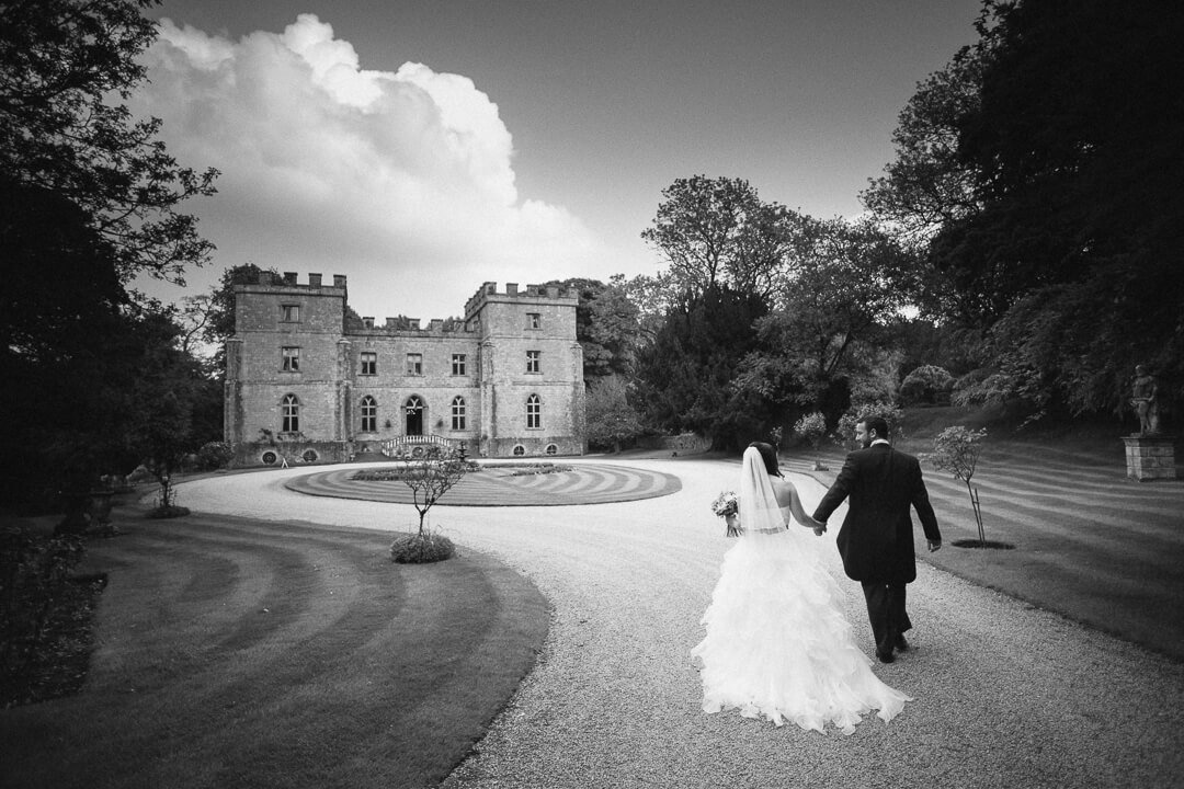 Bride and groom walking hand in hand at Clearwell Castle wedding