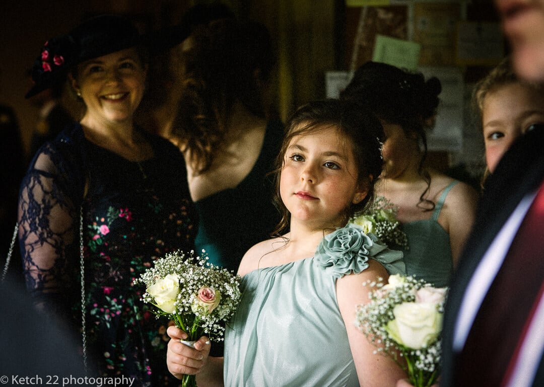Flower girl waiting in church porch at Oxfordshire wedding