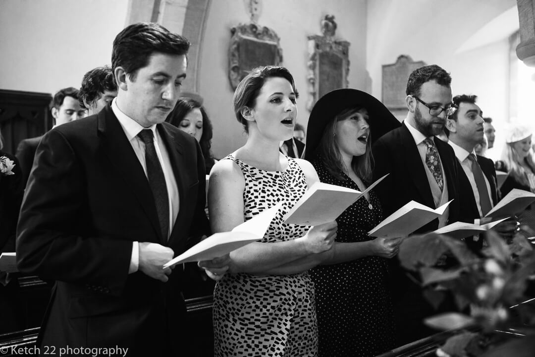 Wedding guests singing in church in Gloucestershire