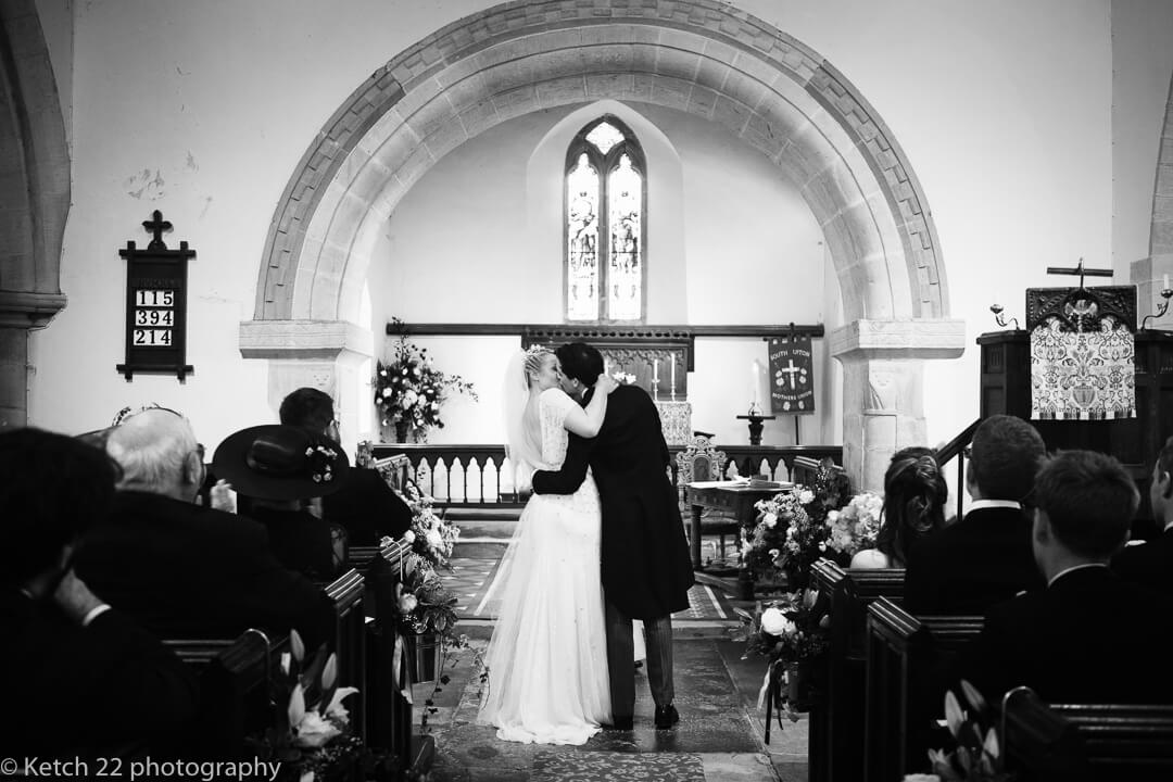 Bride and groom kissing in church at the end of the wedding ceremony