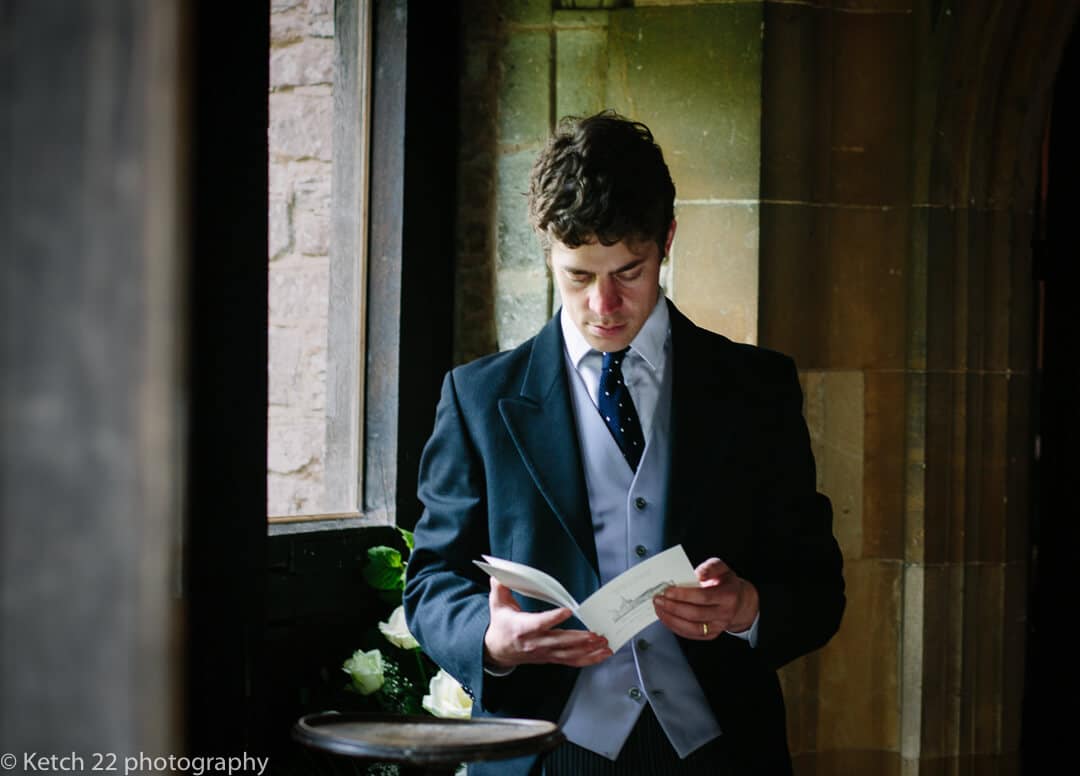 Groomsmen reading wedding service order in Church porch
