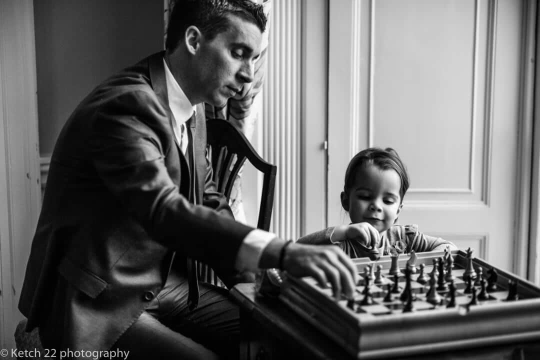 Father and daughter playing chess at photojournalistic wedding 