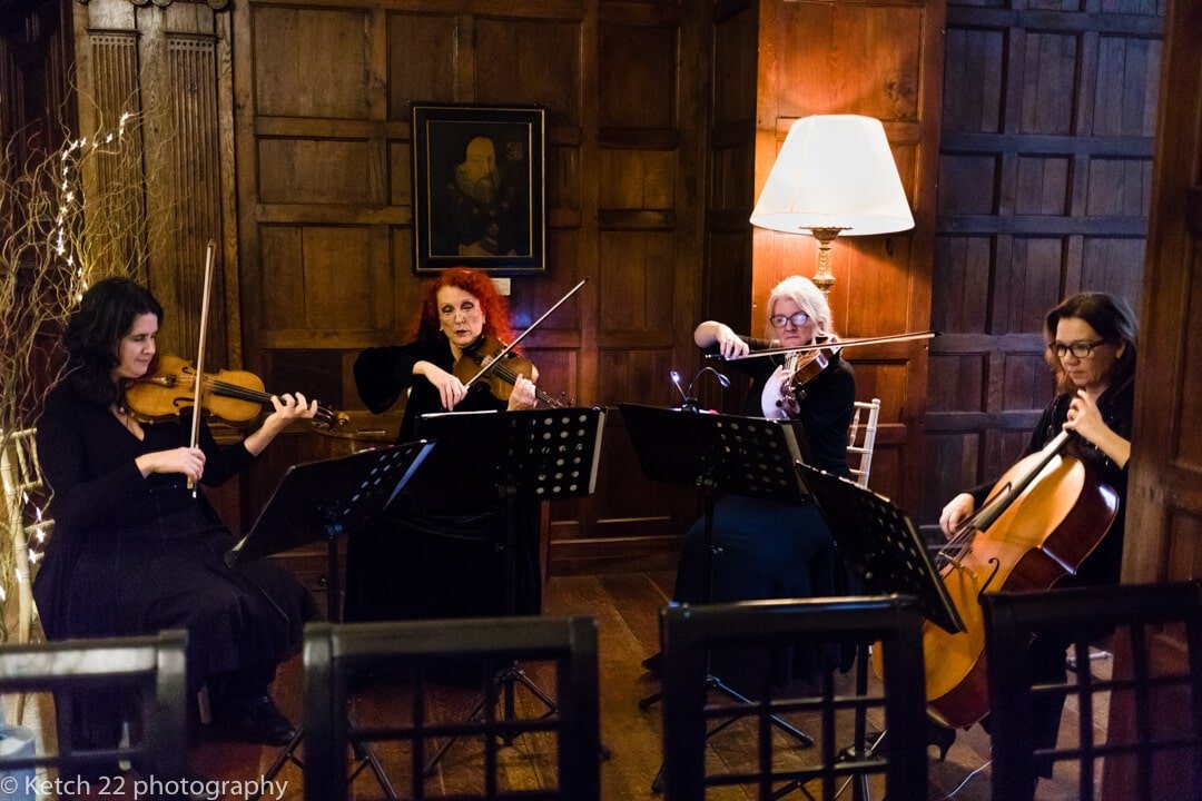 Candid wedding photo of 3 piece orchestra playing music at wedding