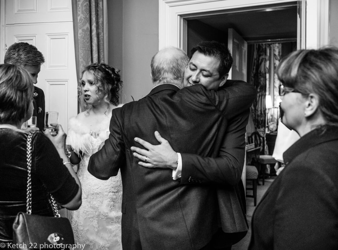 Reportage wedding photography of groom hugging guest