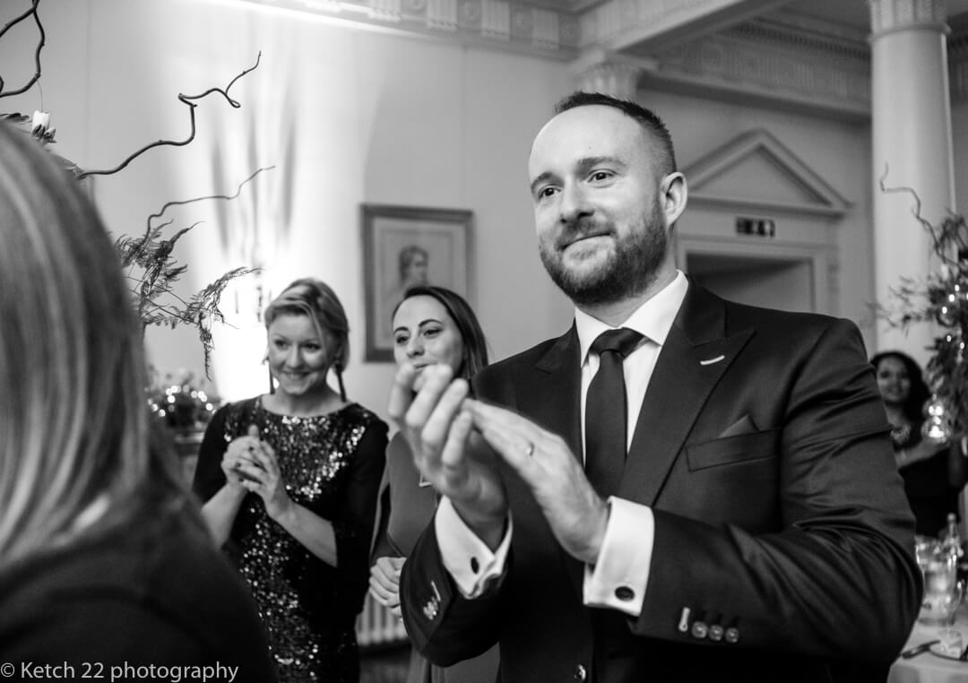 Wedding guests cheering as bride and groom enter dinning room