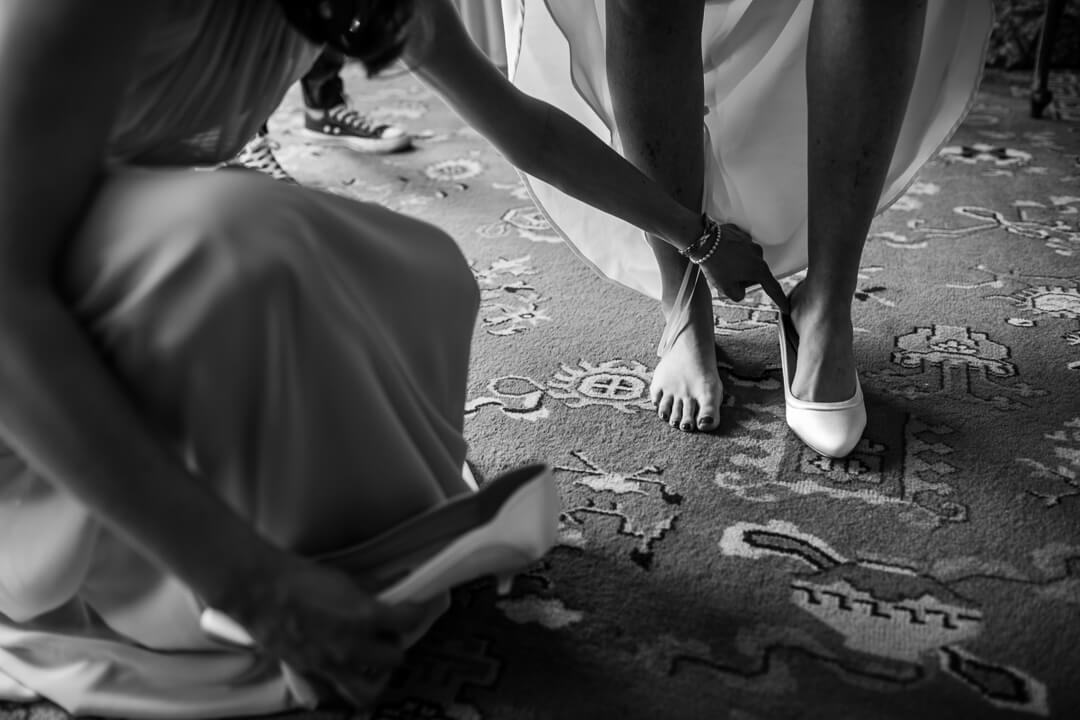 Natural wedding photo of bride putting on shoes