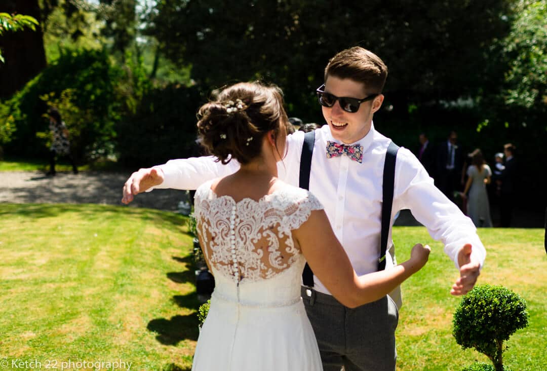 Wedding guest with sunglasses hugging bride