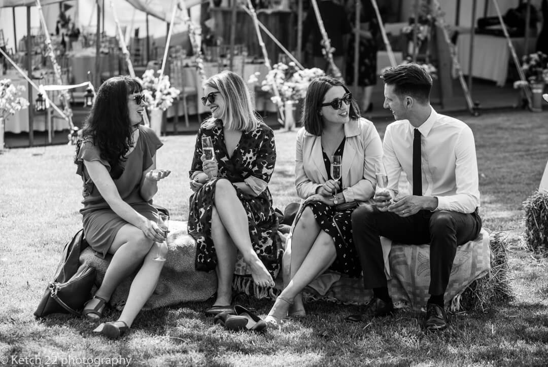 Documentary wedding photo of guests sitting on straw bale